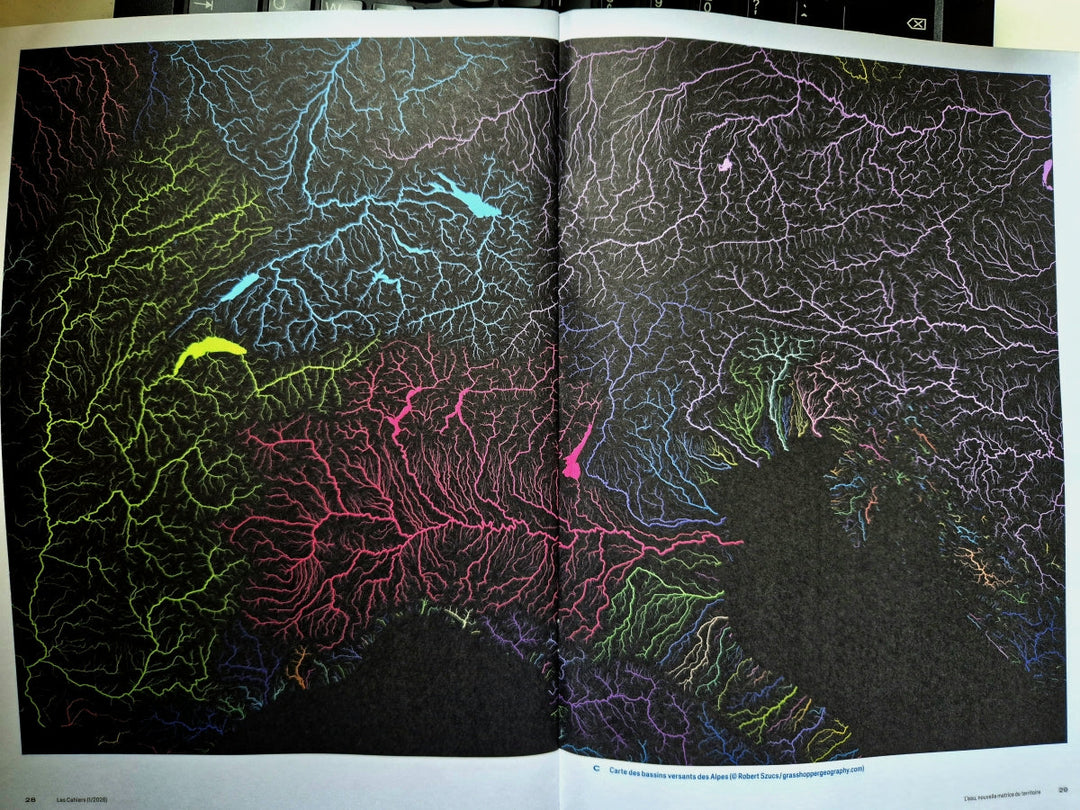 A photo showing the Cahiers d'EspaceSuisse - romande journal open at the double page image of Grasshopper Geography's colourful river basin map of the Alps.