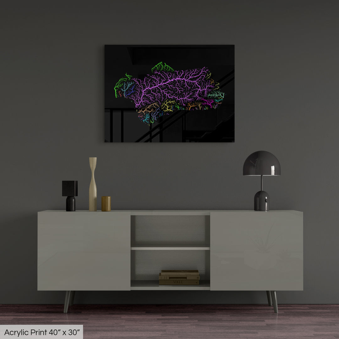 A colourful Grasshopper Geography map, home decor hanging on a grey wall in a living room. The map is printed on an acrylic panel and hangs above a modern low storage cabinet.