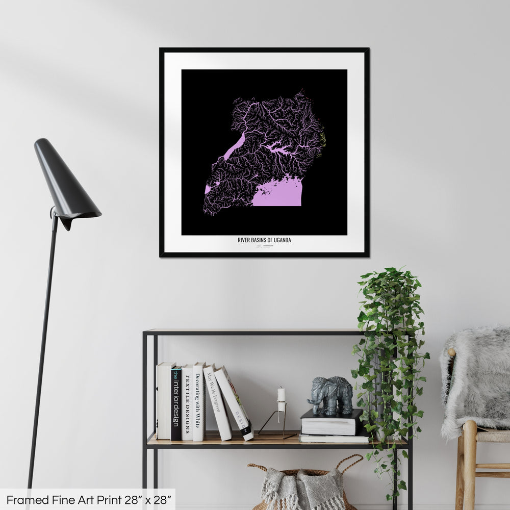 A colourful Grasshopper Geography map on a white wall, home decor in a living room. The map is in a black frame with a thick white mat. The title of the map is printed on the mat. The map hangs above a black shelf with plants and books on. A black lamp stands in the corner.
